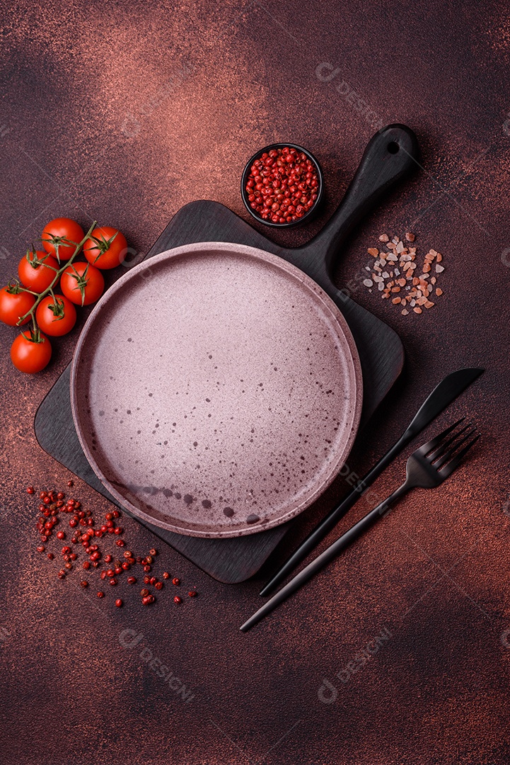 Placa redonda de cerâmica vazia em fundo de concreto texturizado escuro. Talheres, preparação para o jantar
