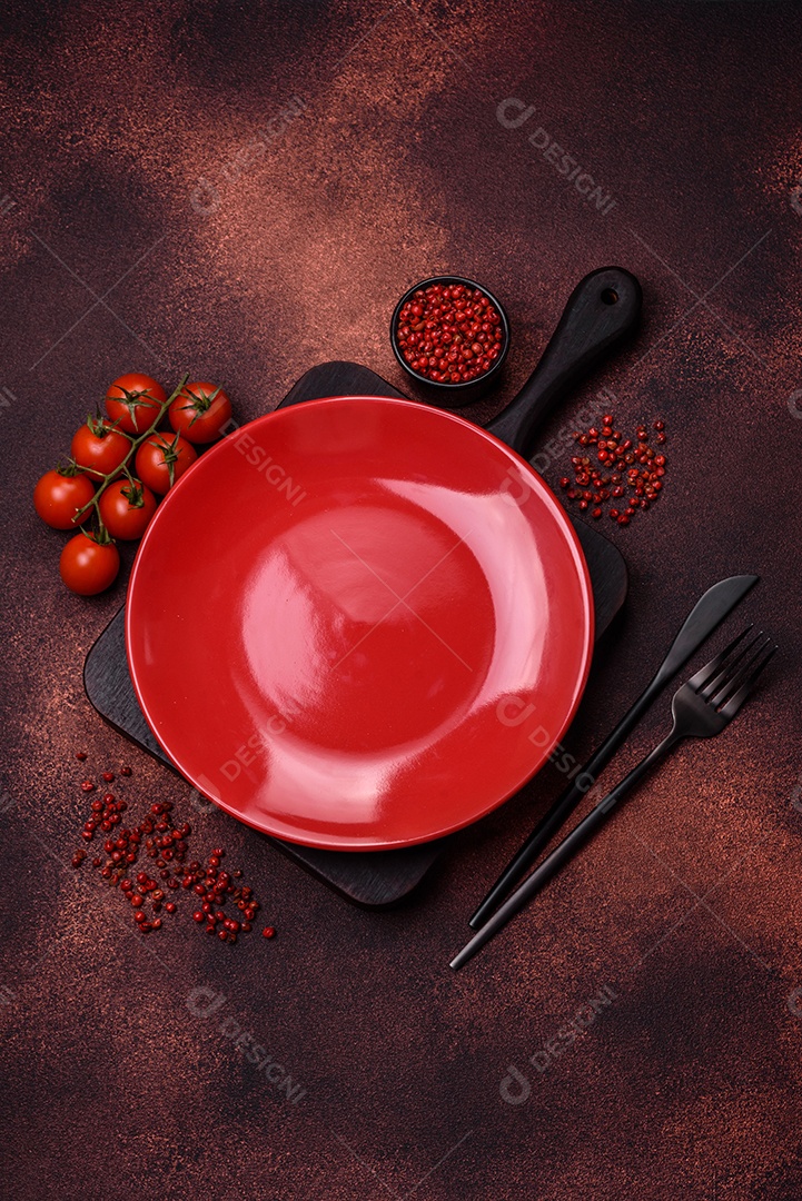 Placa redonda de cerâmica vazia em fundo de concreto texturizado escuro. Talheres, preparação para o jantar