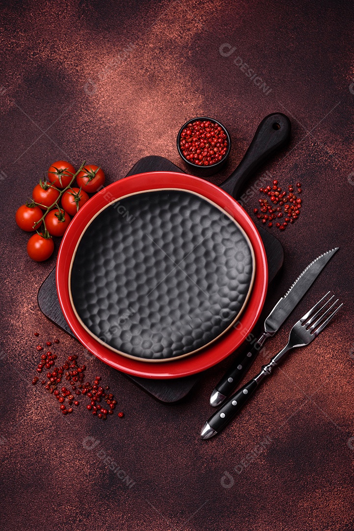 Placa redonda de cerâmica vazia em fundo de concreto texturizado escuro. Talheres, preparação para o jantar