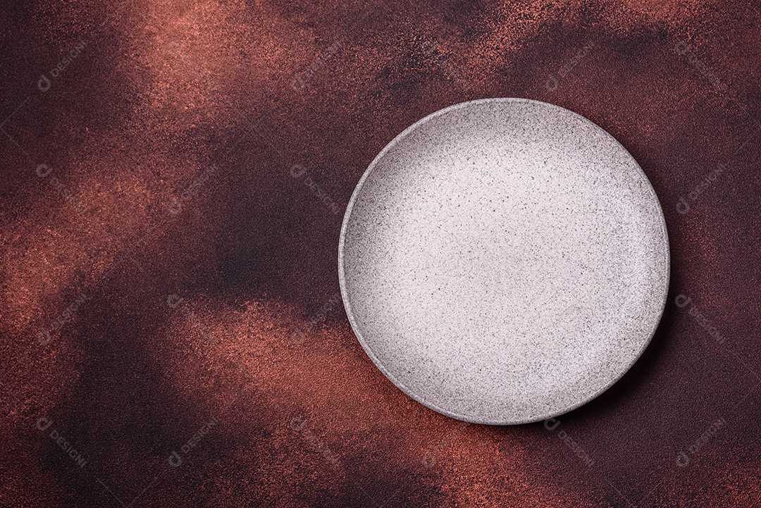 Placa redonda de cerâmica vazia em fundo de concreto texturizado escuro. Talheres, preparação para o jantar