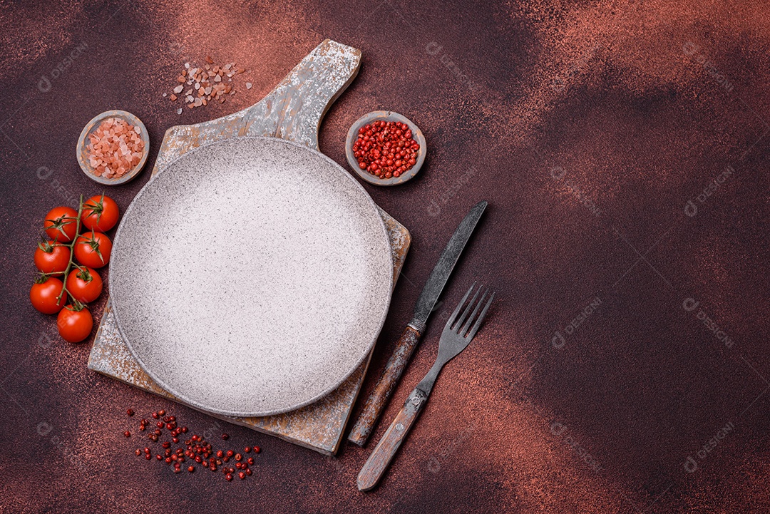 Placa redonda de cerâmica vazia em fundo de concreto texturizado escuro. Talheres, preparação para o jantar