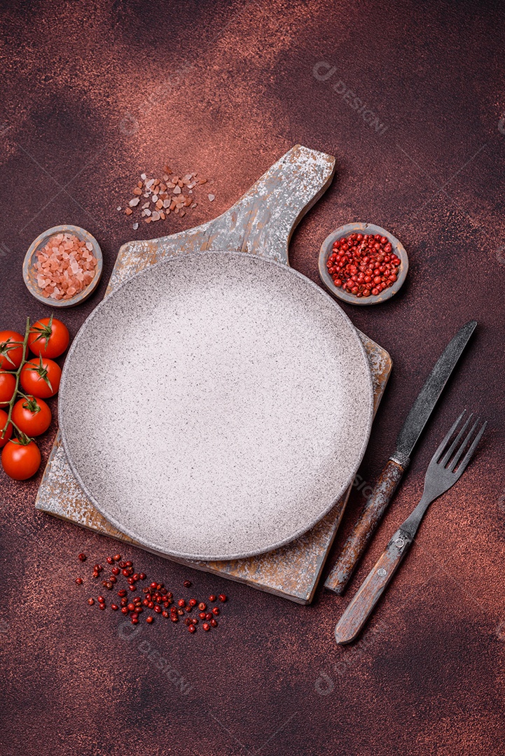 Placa redonda de cerâmica vazia em fundo de concreto texturizado escuro. Talheres, preparação para o jantar