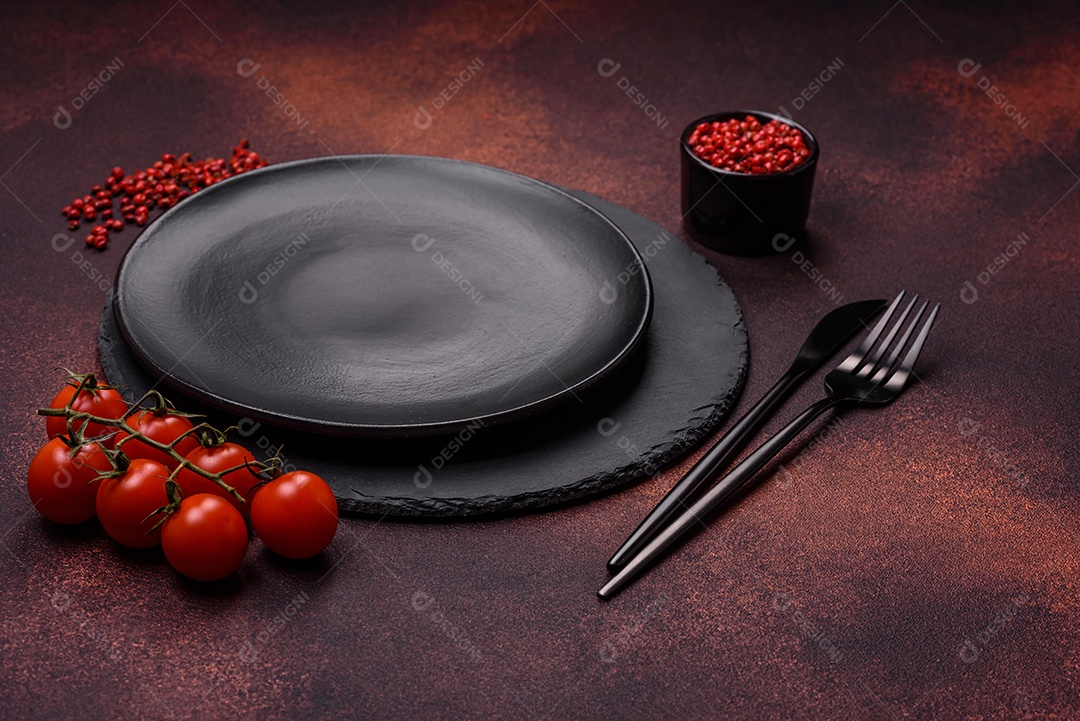 Placa redonda de cerâmica vazia em fundo de concreto texturizado escuro. Talheres, preparação para o jantar