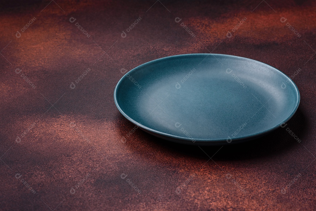 Placa redonda de cerâmica vazia em fundo de concreto texturizado escuro. Talheres, preparação para o jantar
