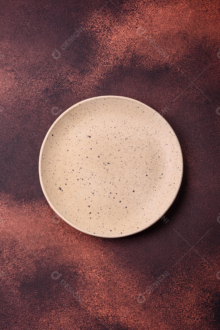 Placa redonda de cerâmica vazia em fundo de concreto texturizado escuro. Talheres, preparação para o jantar