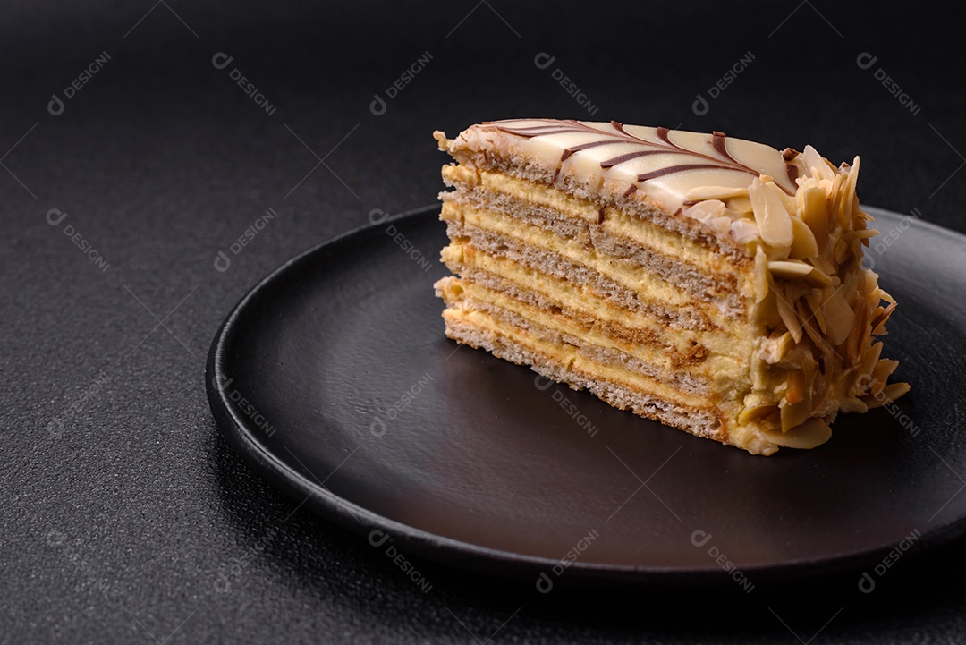 Pedaço de delicioso bolo esterhazy doce com nozes e creme sobre um fundo escuro de concreto