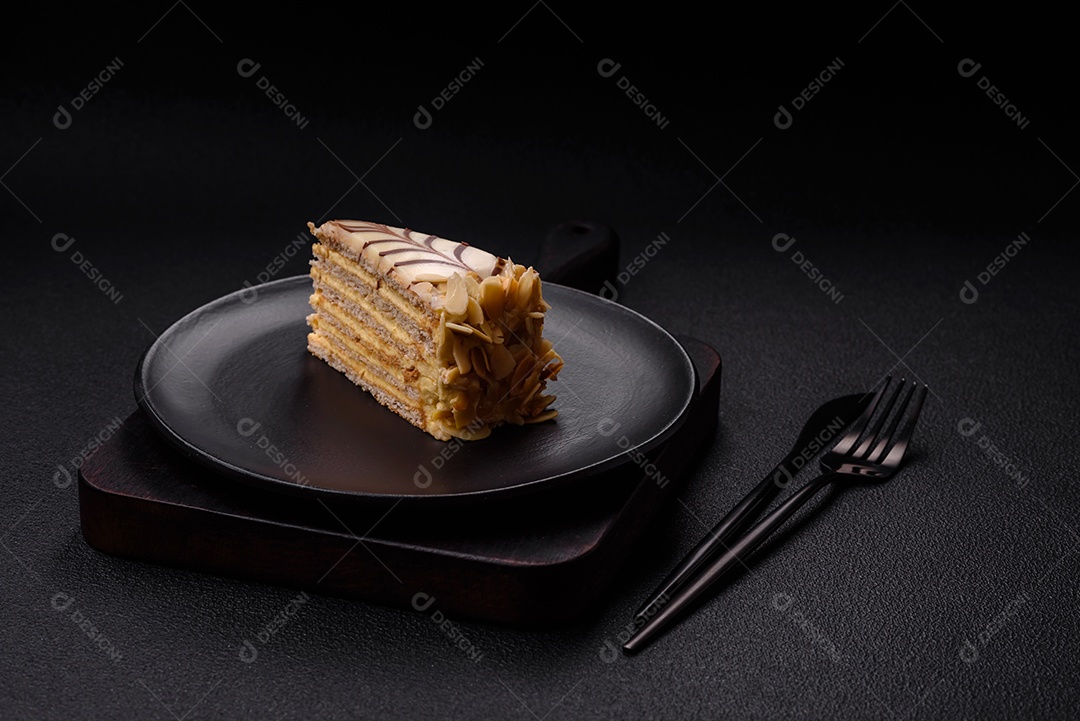 Pedaço de delicioso bolo esterhazy doce com nozes e creme sobre um fundo escuro de concreto