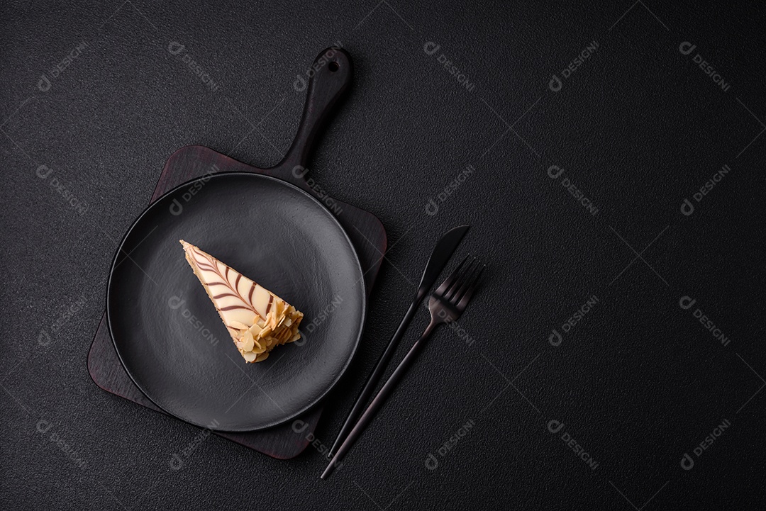 Pedaço de delicioso bolo esterhazy doce com nozes e creme sobre um fundo escuro de concreto