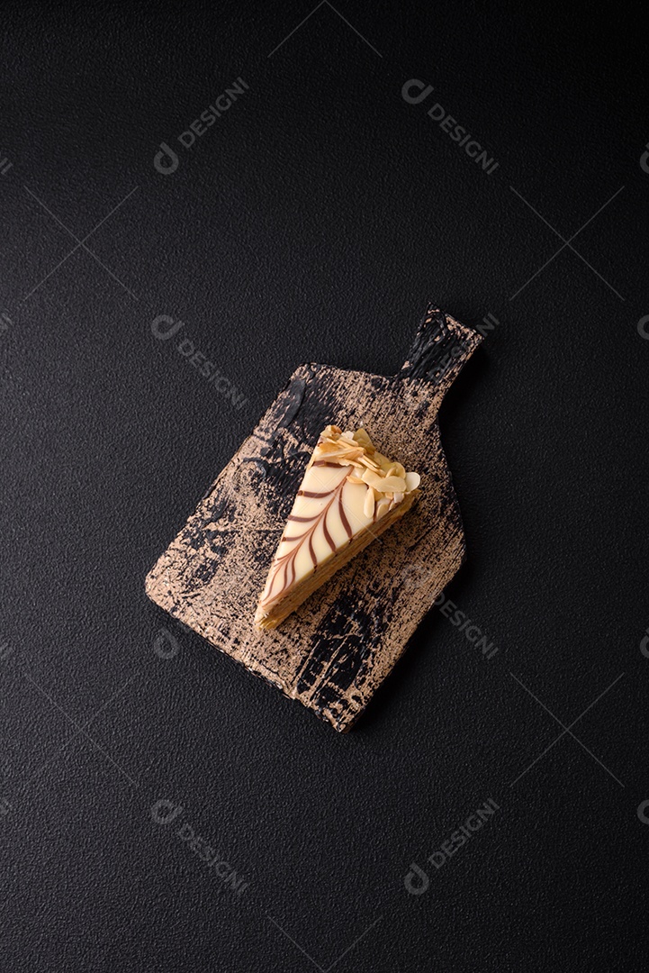 Pedaço de delicioso bolo esterhazy doce com nozes e creme sobre um fundo escuro de concreto