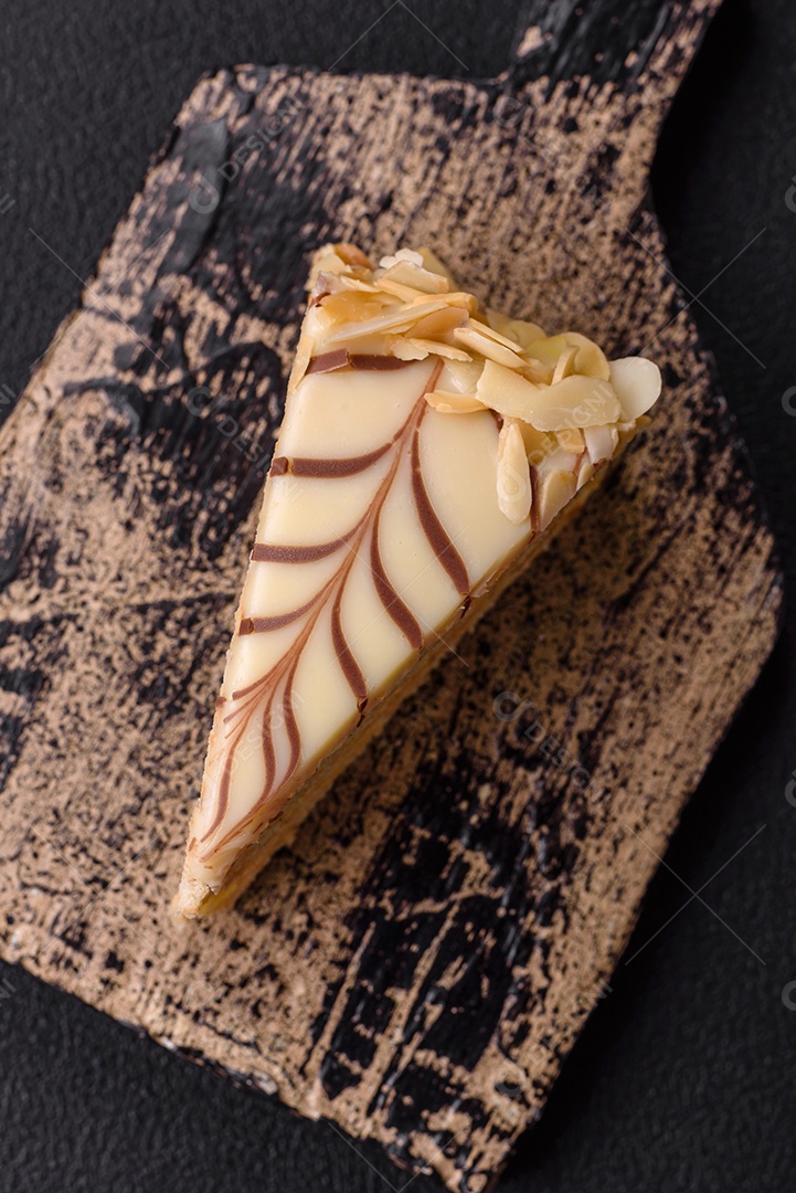 Pedaço de delicioso bolo esterhazy doce com nozes e creme sobre um fundo escuro de concreto