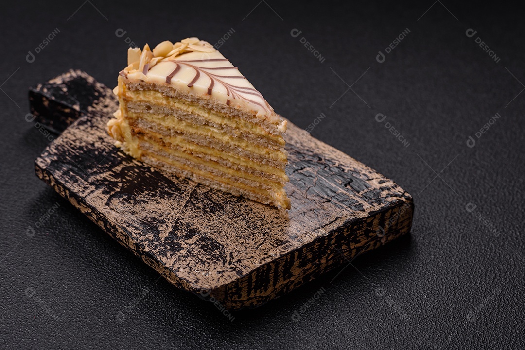 Pedaço de delicioso bolo esterhazy doce com nozes e creme sobre um fundo escuro de concreto