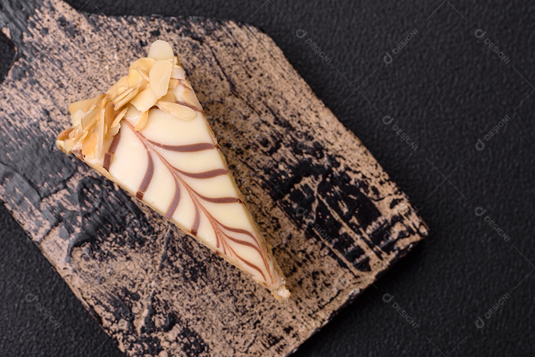 Pedaço de delicioso bolo esterhazy doce com nozes e creme sobre um fundo escuro de concreto