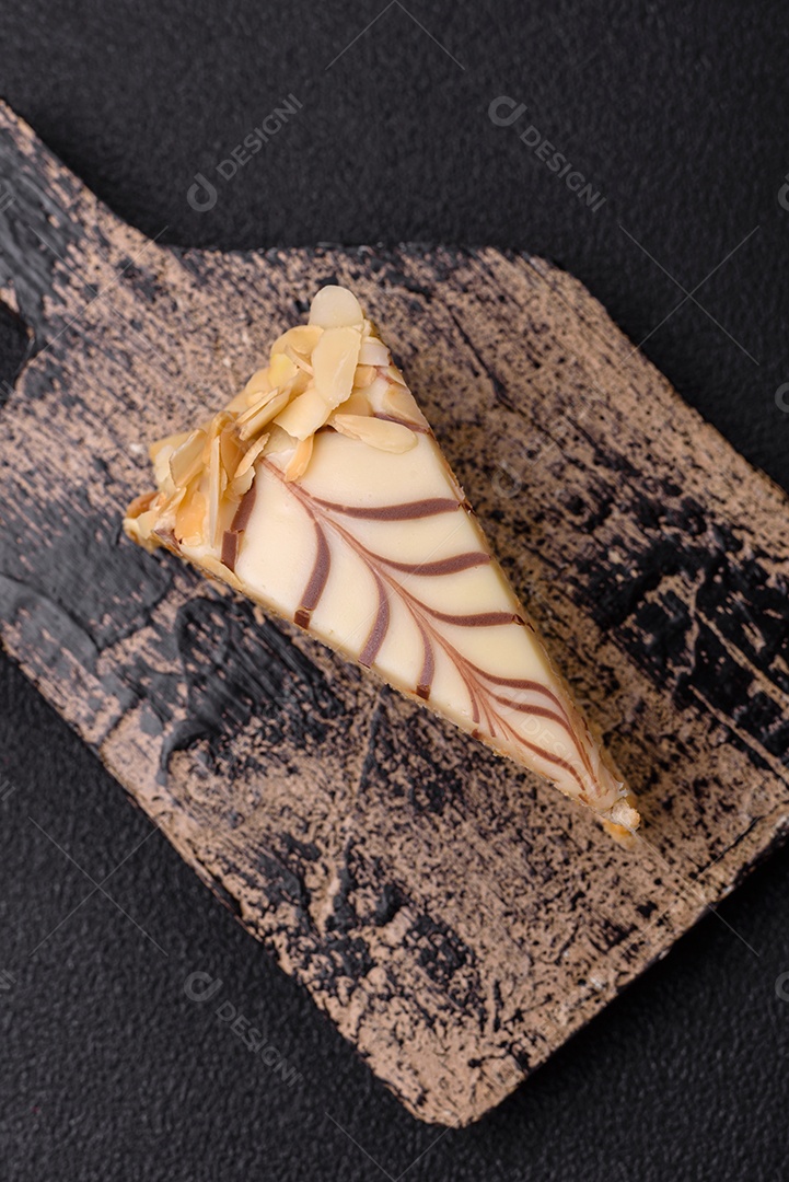 Pedaço de delicioso bolo esterhazy doce com nozes e creme sobre um fundo escuro de concreto