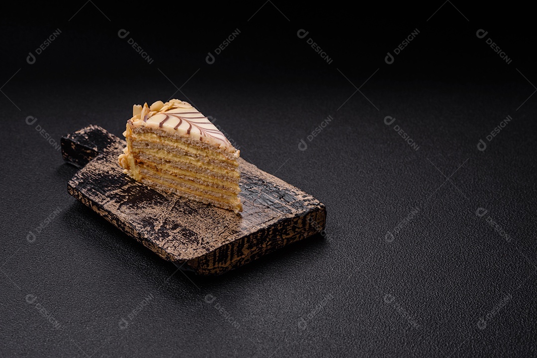 Pedaço de delicioso bolo esterhazy doce com nozes e creme sobre um fundo escuro de concreto
