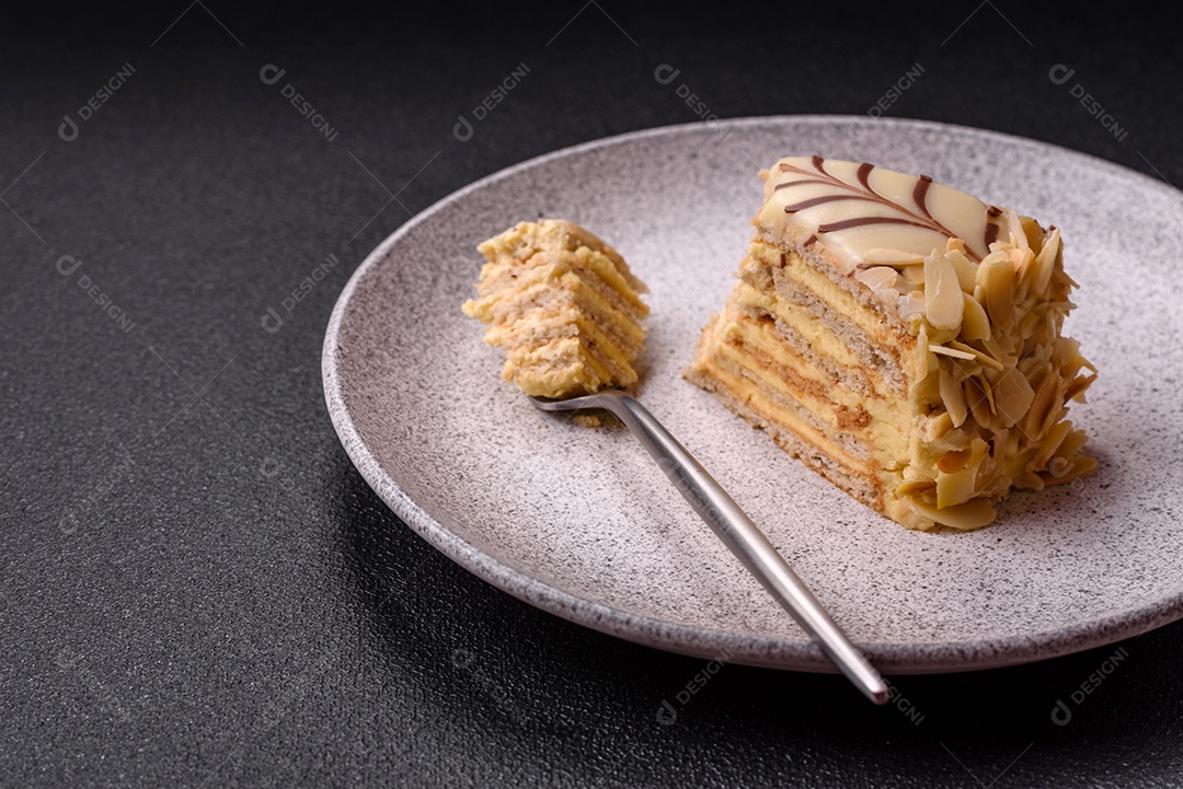 Pedaço de delicioso bolo esterhazy doce com nozes e creme sobre um fundo escuro de concreto