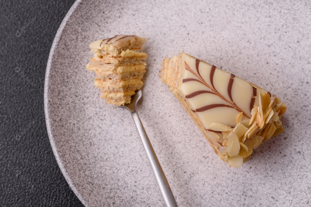 Pedaço de delicioso bolo esterhazy doce com nozes e creme sobre um fundo escuro de concreto