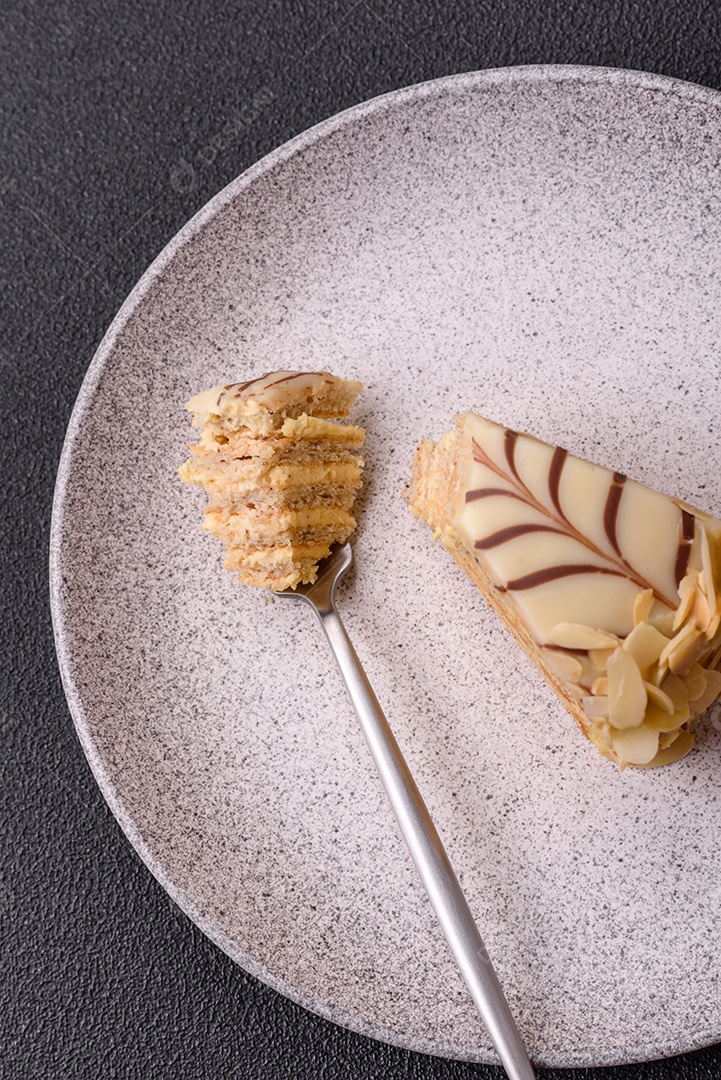 Pedaço de delicioso bolo esterhazy doce com nozes e creme sobre um fundo escuro de concreto