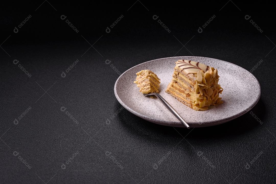 Pedaço de delicioso bolo esterhazy doce com nozes e creme sobre um fundo escuro de concreto