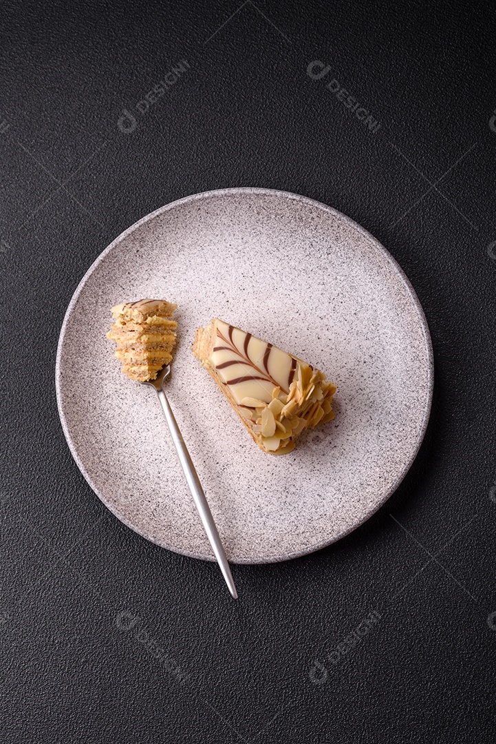 Pedaço de delicioso bolo esterhazy doce com nozes e creme sobre um fundo escuro de concreto
