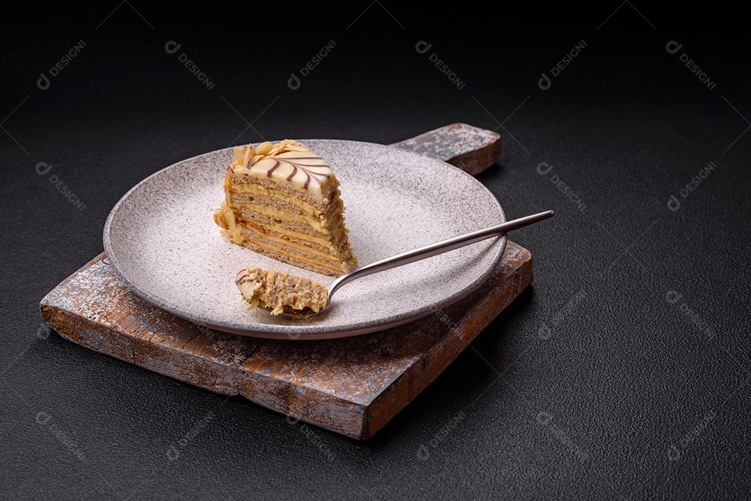 Pedaço de delicioso bolo esterhazy doce com nozes e creme sobre um fundo escuro de concreto