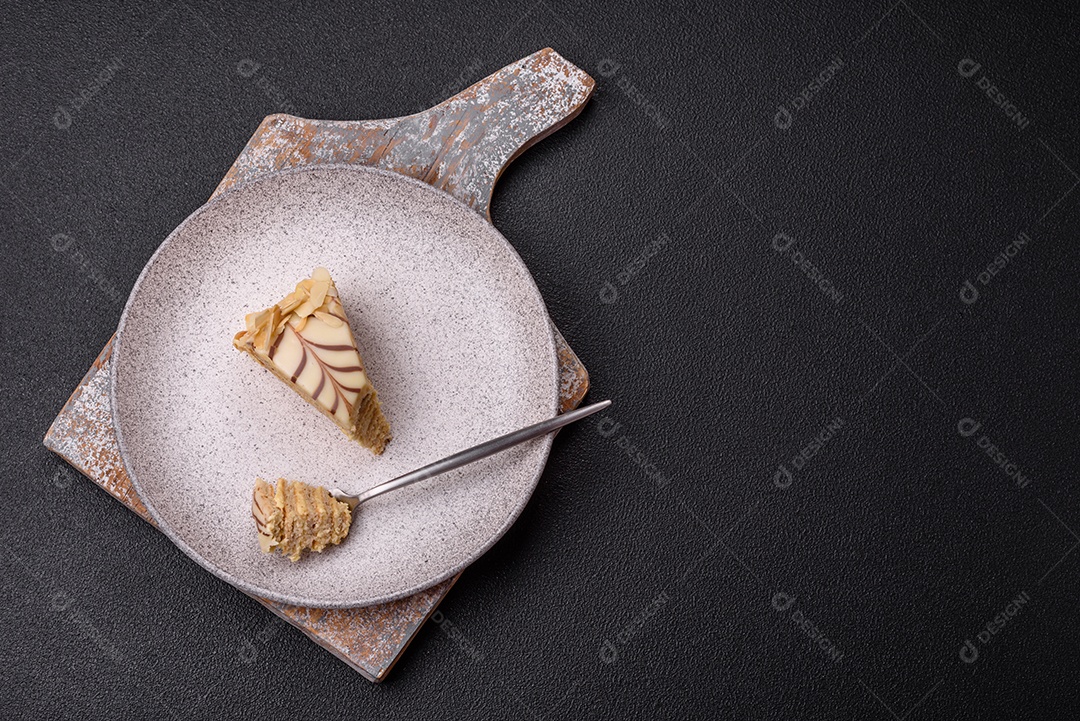 Pedaço de delicioso bolo esterhazy doce com nozes e creme sobre um fundo escuro de concreto