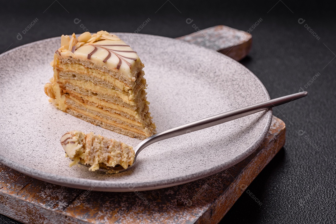 Pedaço de delicioso bolo esterhazy doce com nozes e creme sobre um fundo escuro de concreto