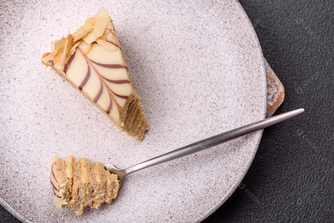 Pedaço de delicioso bolo esterhazy doce com nozes e creme sobre um fundo escuro de concreto