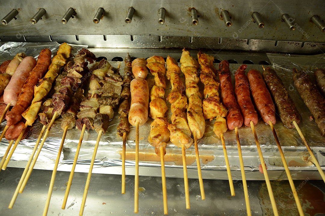 Vários espetos de carnes variadas sobre uma bancada