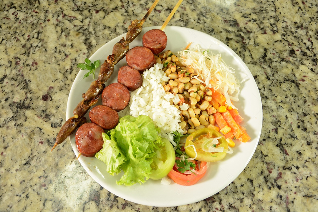 Prato com arroz e feijão e salada espeto de carnes