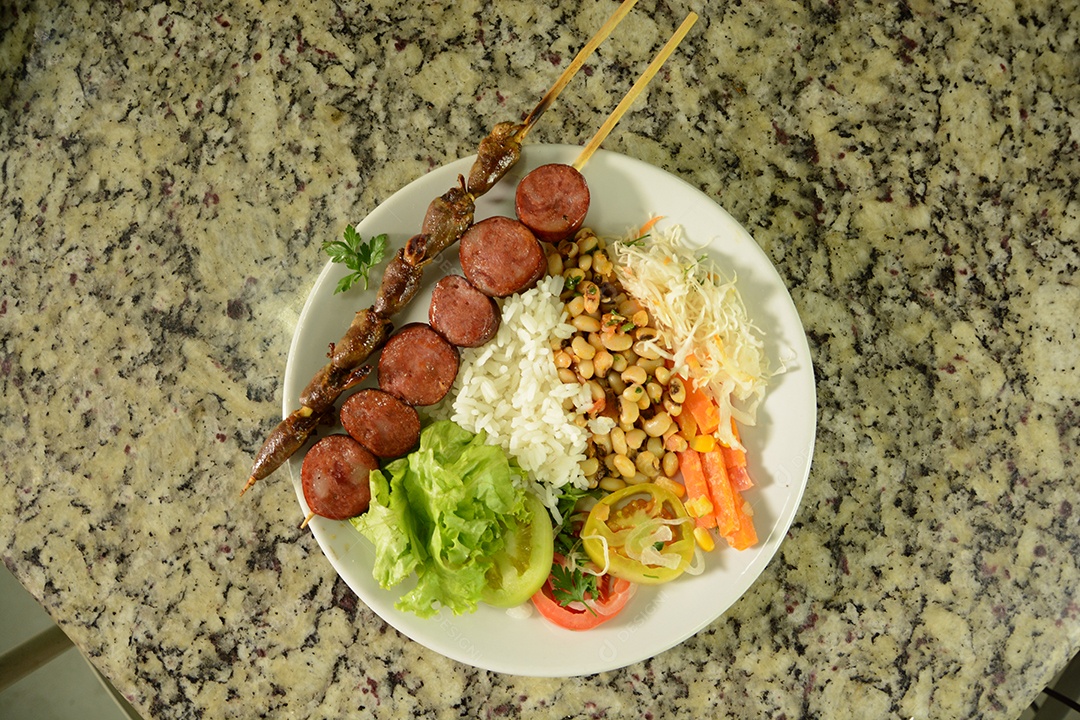 Prato tradicional com espetinhos arroz feijão salada