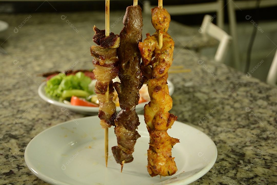 Espetinhos delicioso de carne e frango com fundo de salada