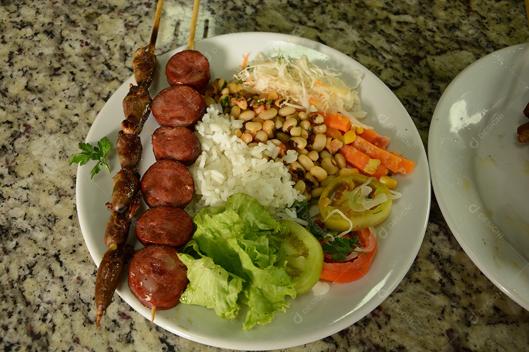Prato delicioso com espetinho arroz feijão e salada