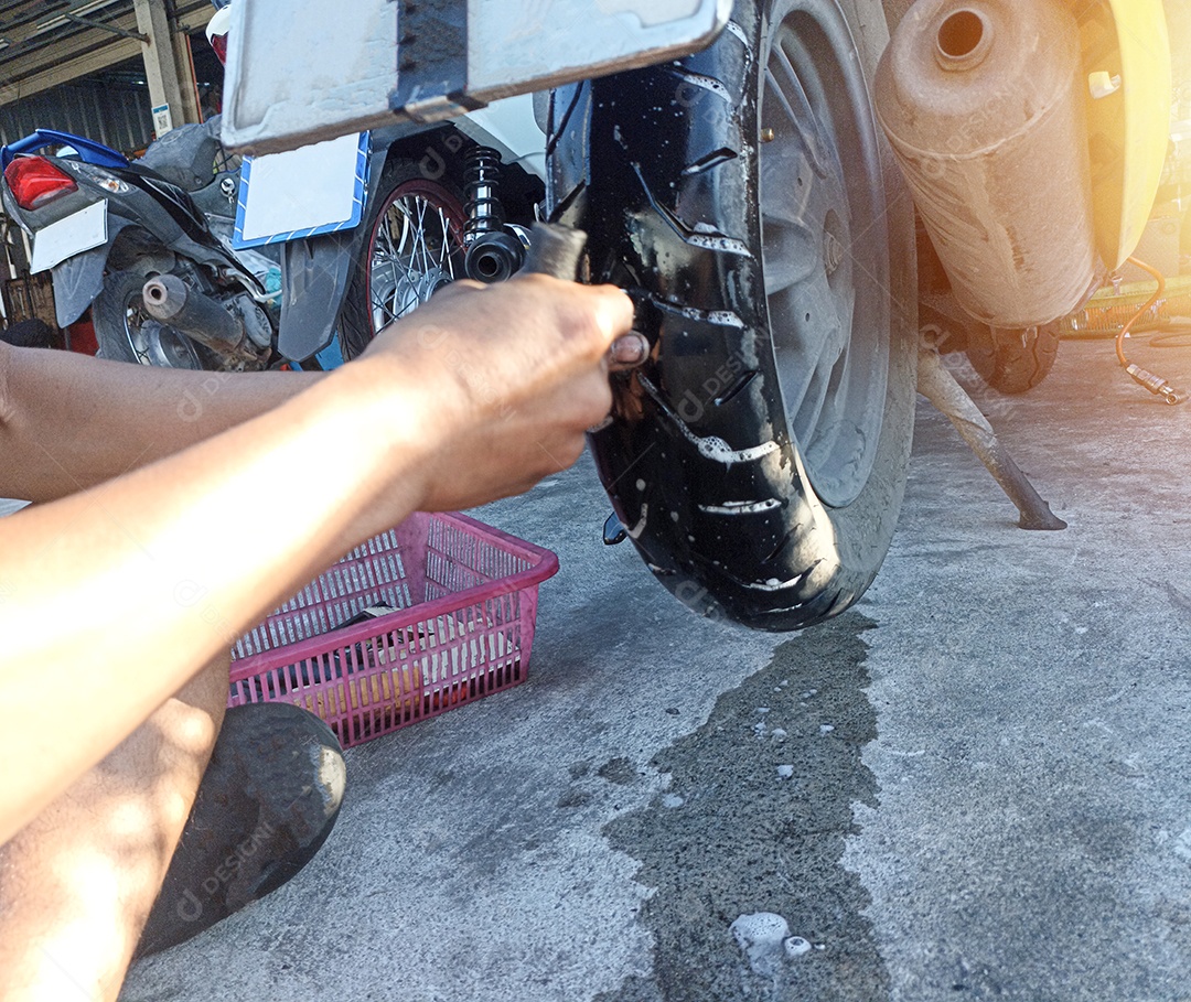 Um mecânico de motocicleta está consertando um pneu furado