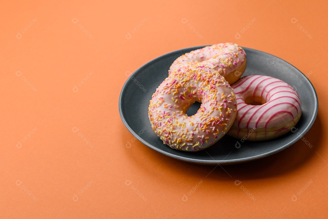Deliciosos donuts doces e brilhantes com creme em um fundo liso. Atributo da tabela de feriados