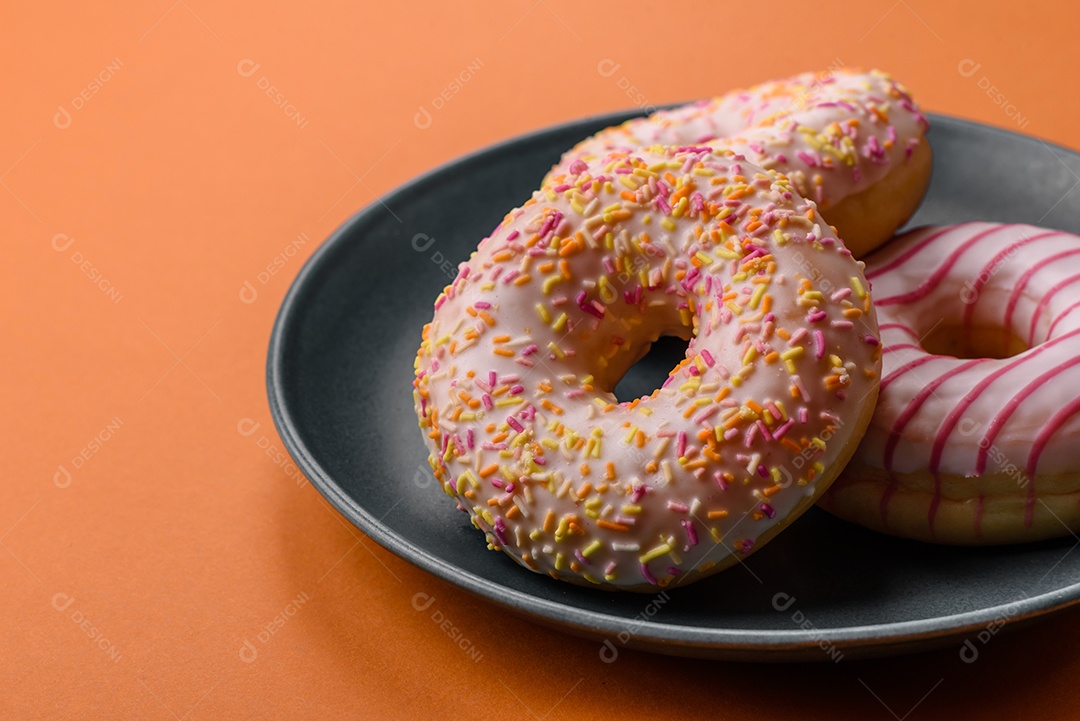 Deliciosos donuts doces e brilhantes com creme em um fundo liso. Atributo da tabela de feriados