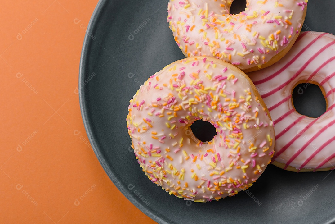 Deliciosos donuts doces e brilhantes com creme em um fundo liso. Atributo da tabela de feriados