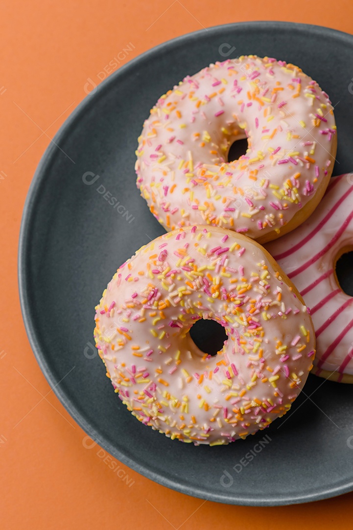 Deliciosos donuts doces e brilhantes com creme em um fundo liso. Atributo da tabela de feriados