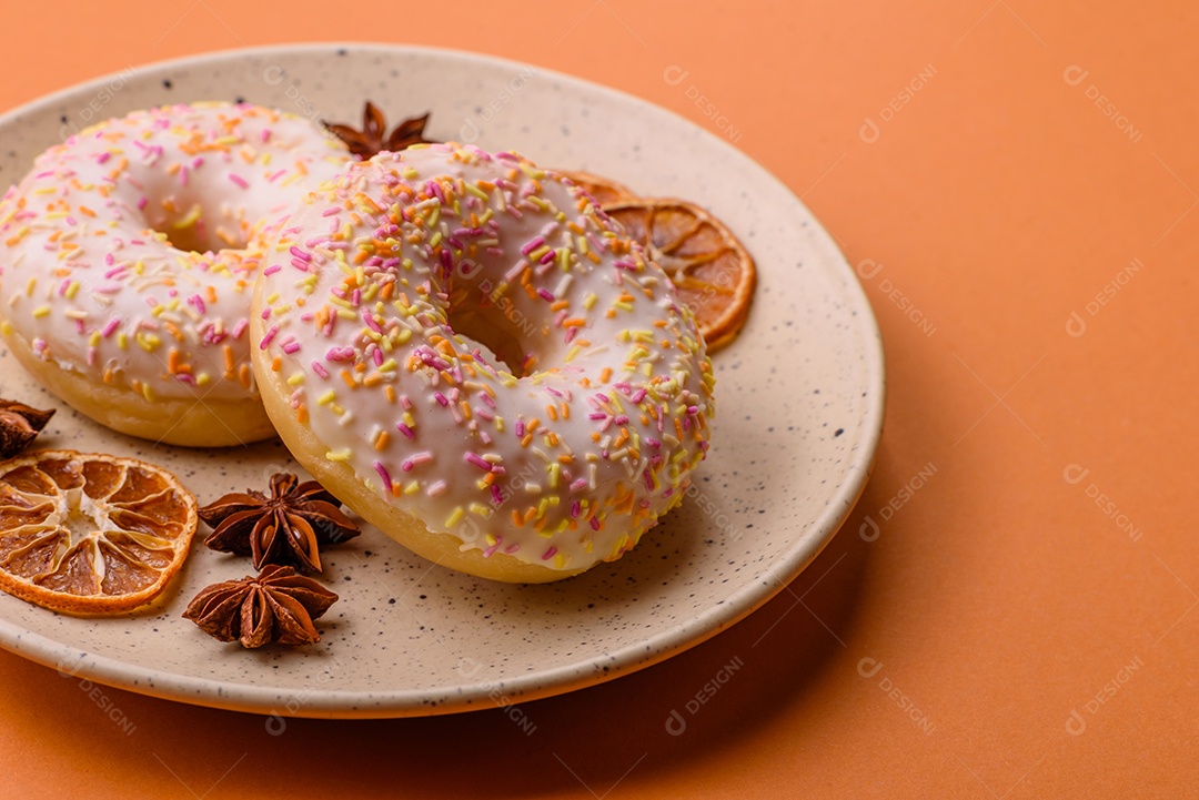 Deliciosos donuts doces e brilhantes com creme em um fundo liso. Atributo da tabela de feriados