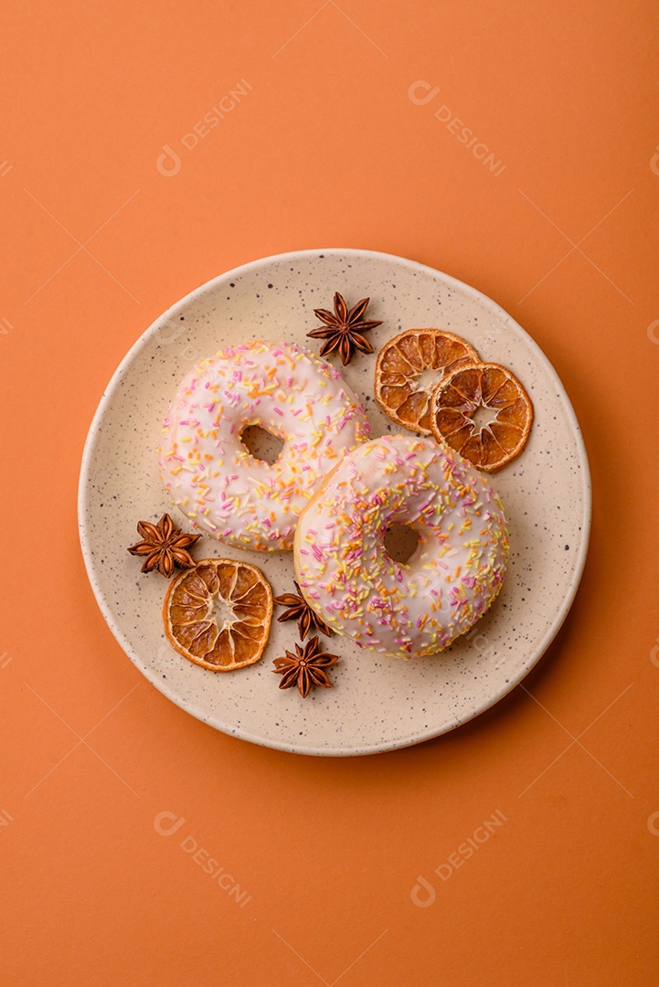 Deliciosos donuts doces e brilhantes com creme em um fundo liso. Atributo da tabela de feriados