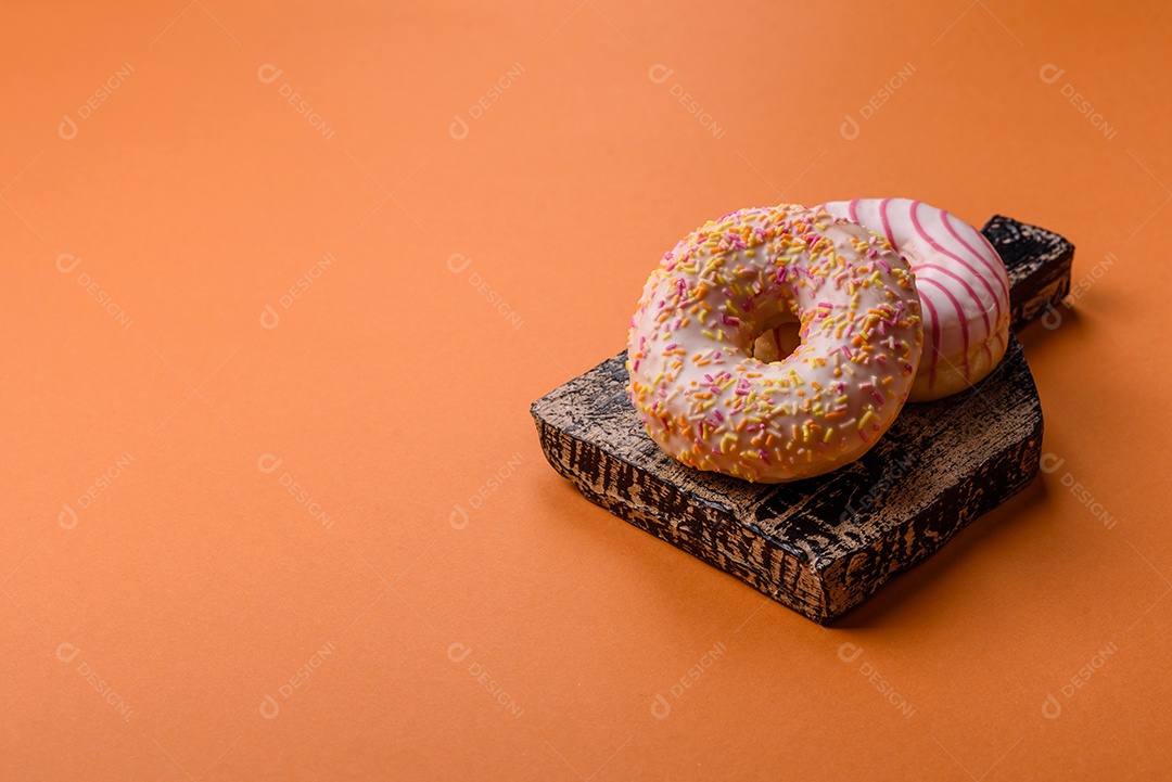 Deliciosos donuts doces e brilhantes com creme em um fundo liso. Atributo da tabela de feriados