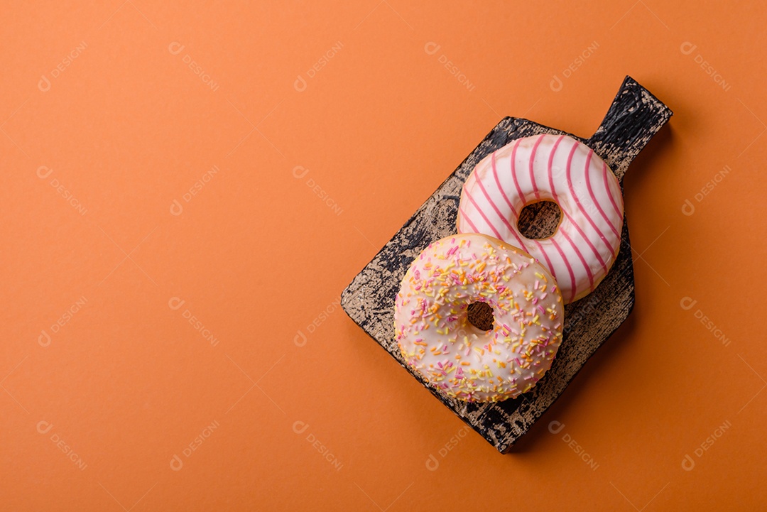 Deliciosos donuts doces e brilhantes com creme em um fundo liso. Atributo da tabela de feriados