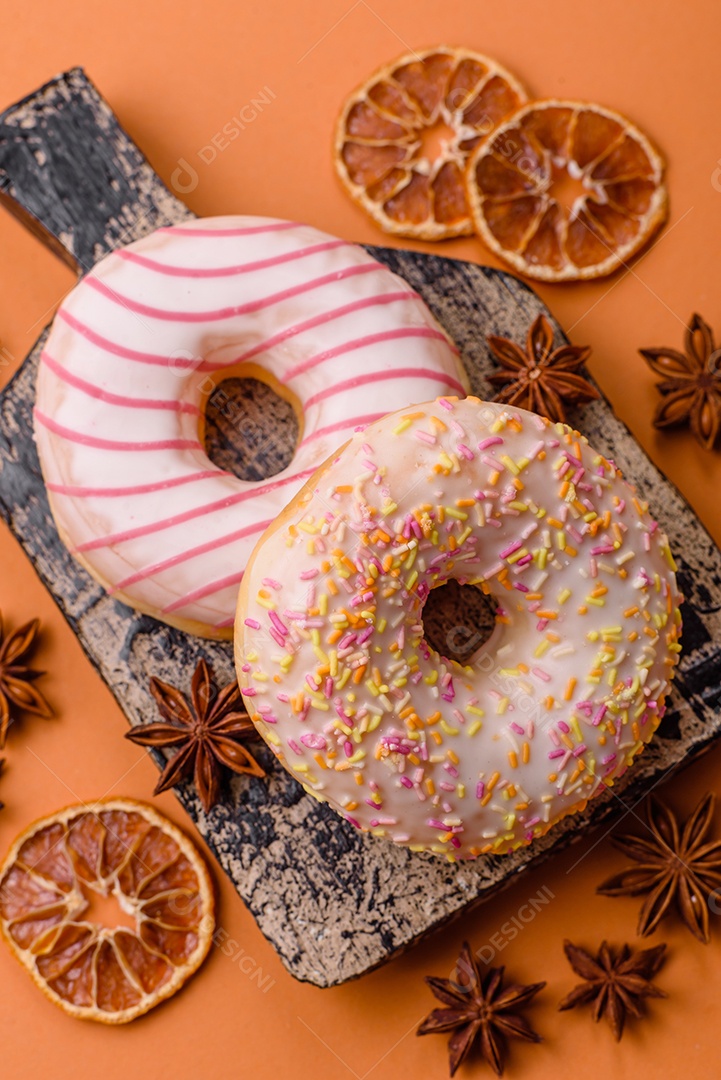 Deliciosos donuts doces e brilhantes com creme em um fundo liso. Atributo da tabela de feriados