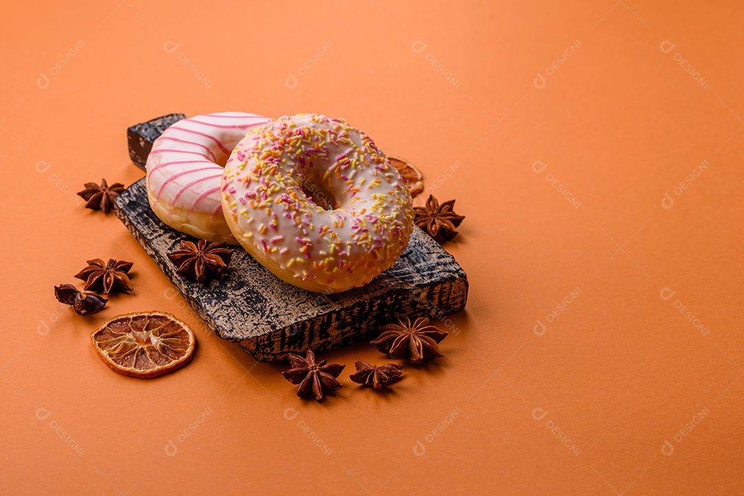 Deliciosos donuts doces e brilhantes com creme em um fundo liso. Atributo da tabela de feriados