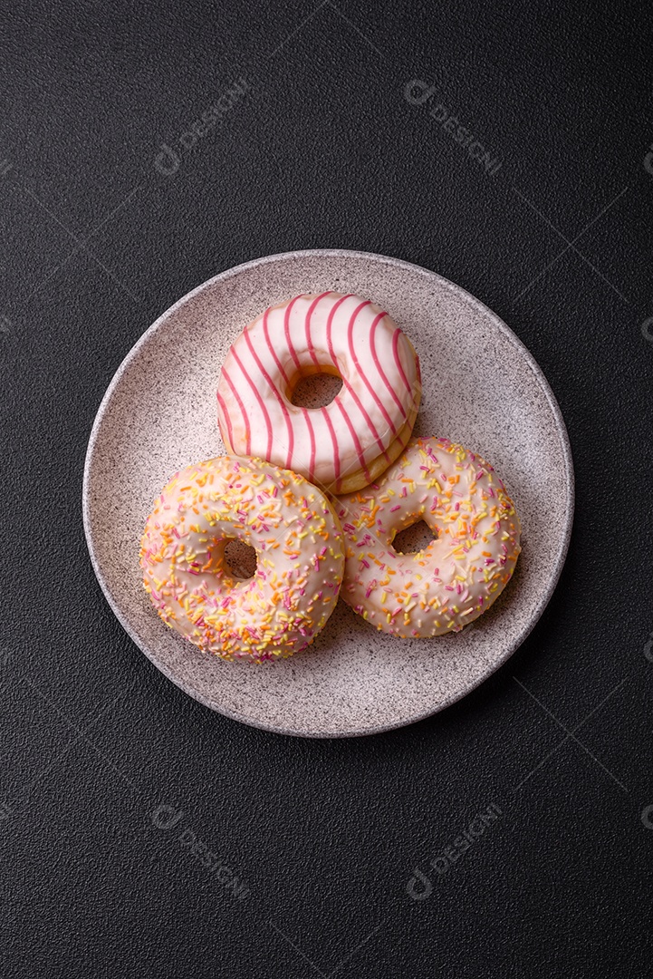 Deliciosos donuts doces e brilhantes com creme em um fundo liso. Atributo da tabela de feriados