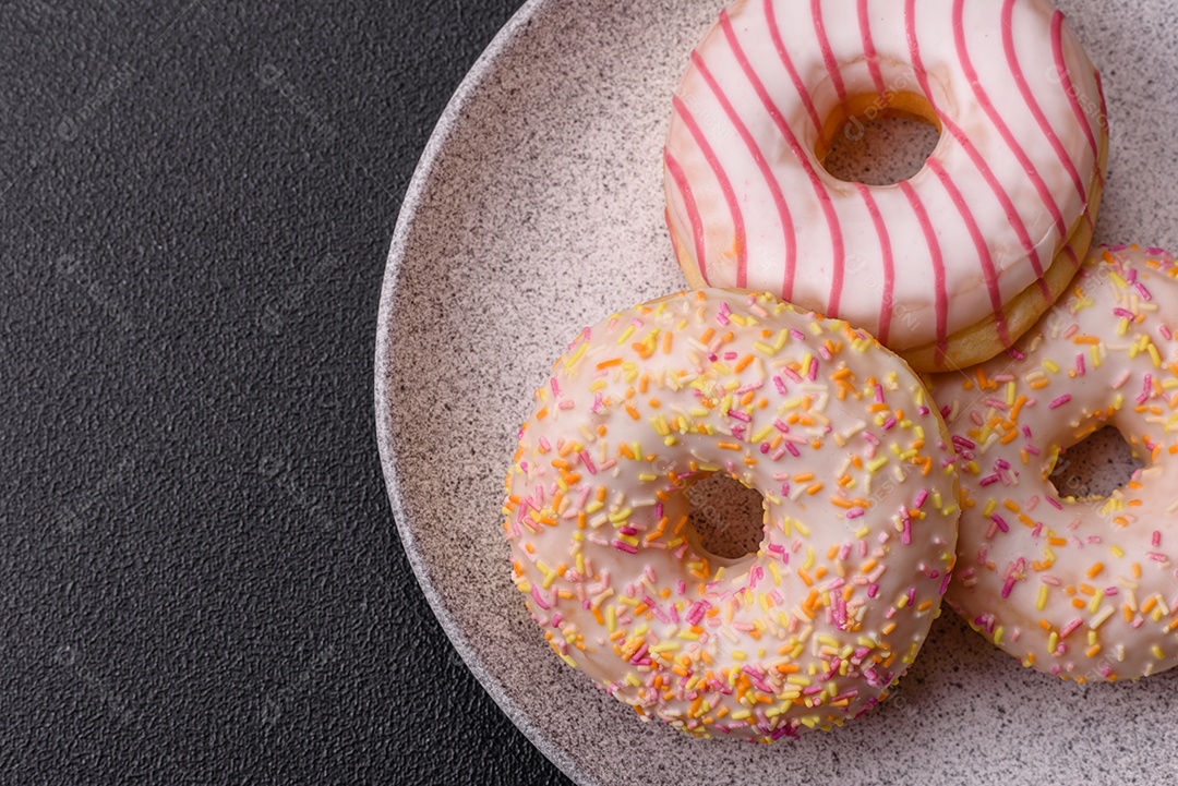 Deliciosos donuts doces e brilhantes com creme em um fundo liso. Atributo da tabela de feriados