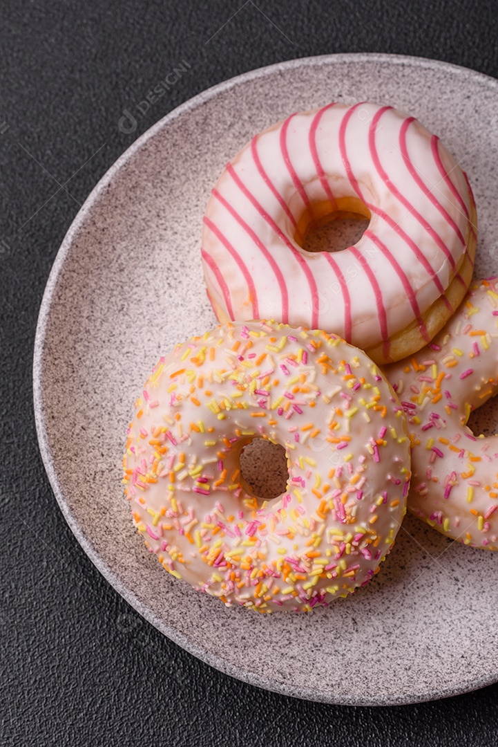 Deliciosos donuts doces e brilhantes com creme em um fundo liso. Atributo da tabela de feriados