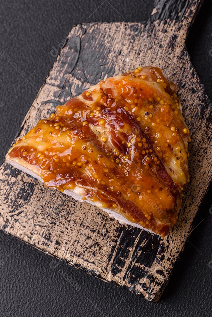 Delicioso presunto ou carne de frango com sal, especiarias e mostarda francesa sobre um fundo escuro de concreto