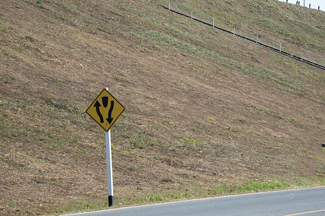 Uma placa de trânsito indica um cruzamento à esquerda à frente