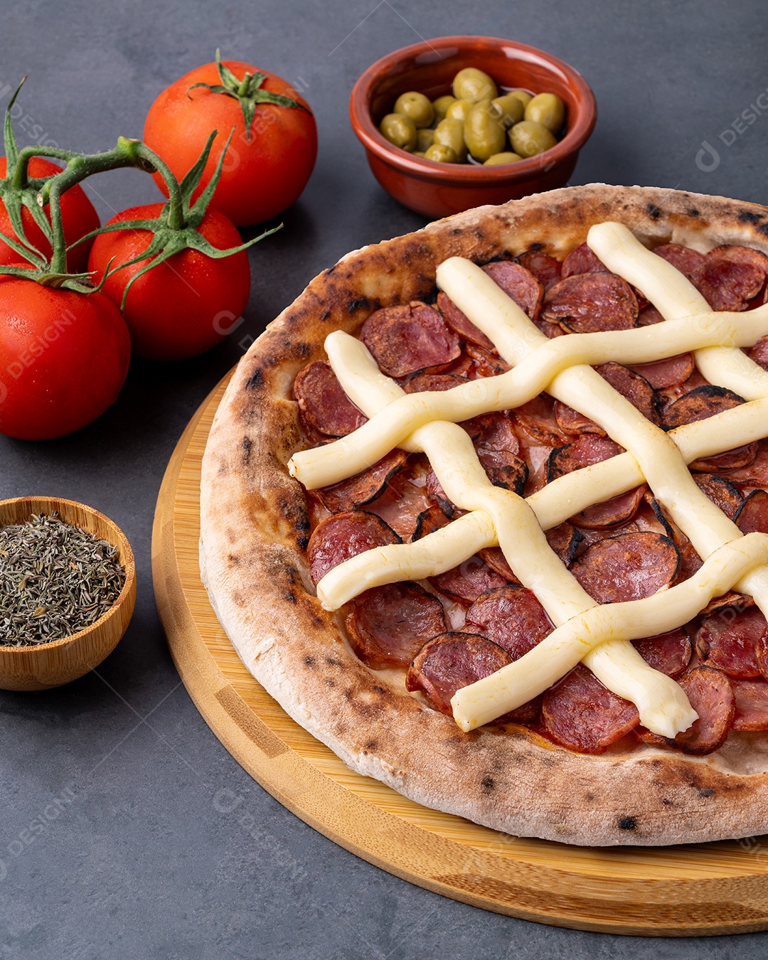 Pizza calabresa catupiry sobre tábua ao lado ingredientes azeitona tomate oregano