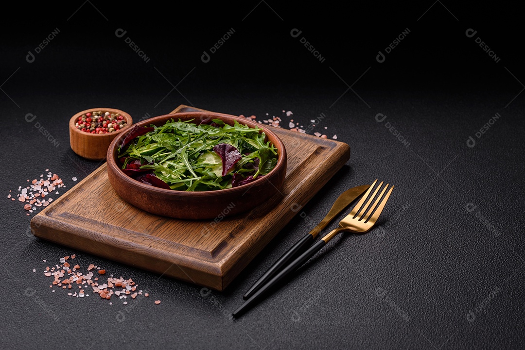 Deliciosa salada suculenta com salmão, tomate, pepino, ervas, sementes de abóbora, sal e especiarias em uma placa cerâmica sobre um fundo escuro de concreto